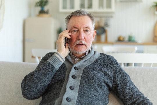 Happy middle aged senior man talking on smartphone with family friends. Older mature grandfather with cell phone talking with grown up children, resting at home. Older generation modern tech usage