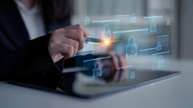 Business professional interacting with digital interface showcasing padlocks and cybersecurity symbols on a tablet screen in modern office setting. Entropy.