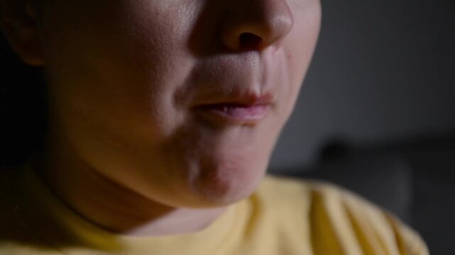 Close up of a young woman's lips as she eats corn rings. Food-focused scene highlighting texture, chewing and snacking behavior.