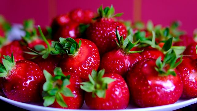 Fresh ripe strawberries on white plate over terracotta background on black table close up summer berry harvest