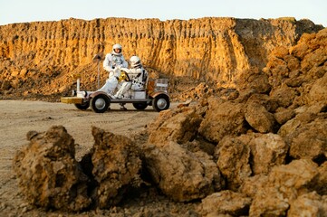 Exploration on Mars with astronauts driving a rover near rocky terrain at sunset © Kokhan O