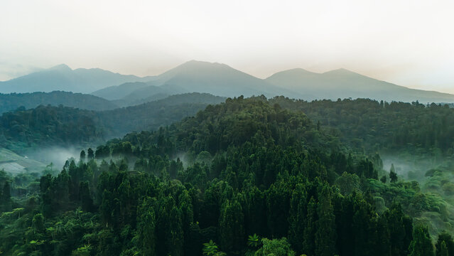 Aerial view of lush tropical forest and misty mountain ranges under a hazy morning sky Sukabumi, West Java, Indonesia.
