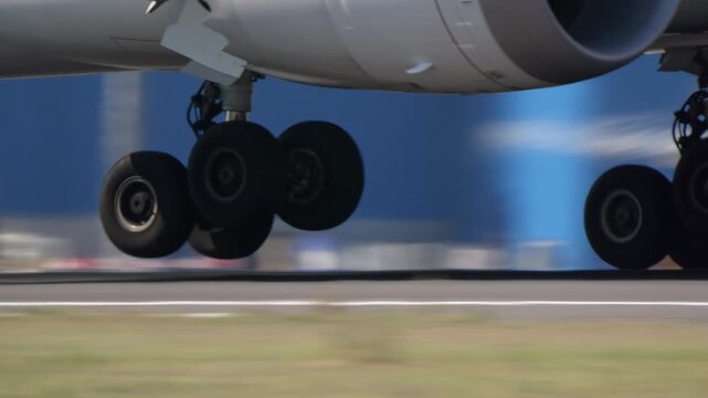 Extreme closeup of a wide body commercial aircraft main landing gear bogies during high speed takeoff run, motion blur background, airport runway, daylight.