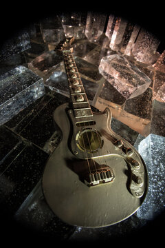 Music Concept: Guitar Miniature on a Dark Background with Vivid Light, Smoke, and Fire Effects. Golden electro guitar under a Dramatic Spotlight.