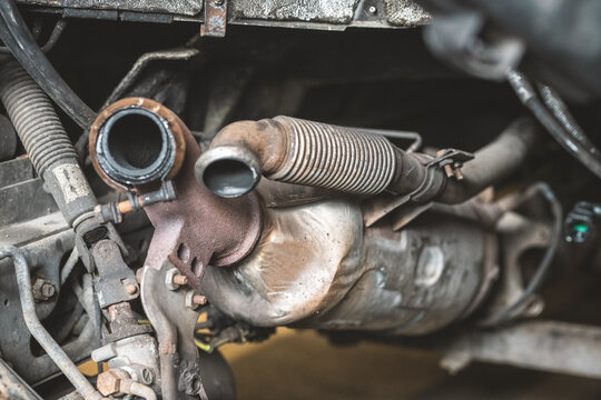 Close-up of a rusty catalytic converter and exhaust system components