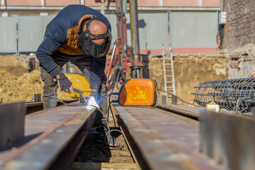 Fototapeta premium Construction worker welding metal beam at building site