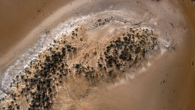 Aerial view of the salt crust and arid landscape of Lake Tyrrell with scattered shrubs and textured red earth in Buloke Shire, Victoria, Australia.