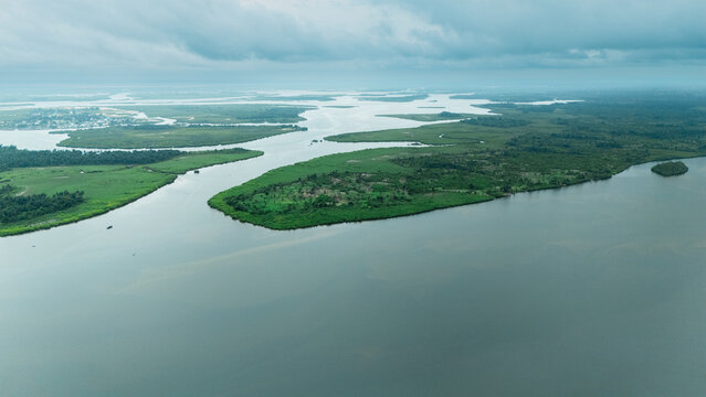 Aerial view of lush green islands and winding river channels under a cloudy sky in the Niger Delta region, Rivers State, Nigeria.