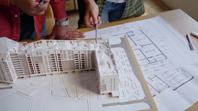 Architect professionals point at building model roof in office