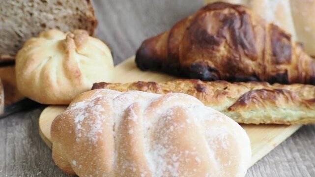 On the table are fresh bread and pastries, apple buns, pies, and croissants. Fresh, warm pastries topped with cheese are displayed in the bakery's display case.