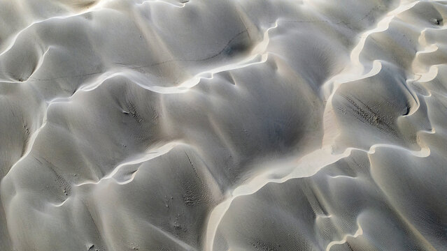 Aerial view of intricate sand dunes with wind-swept ripples and soft shadows at Magdalena Bay Mexico.