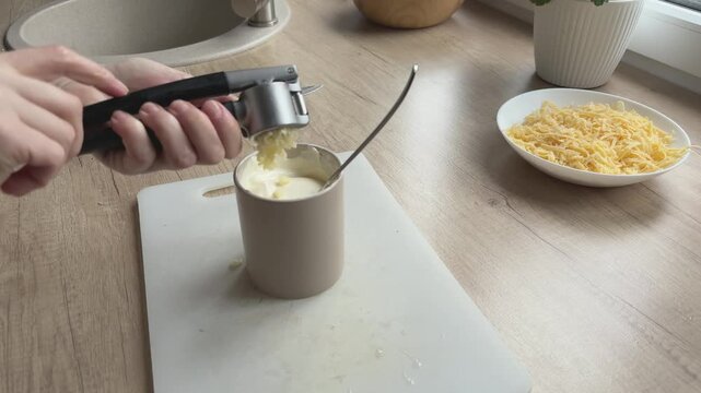 Close angle pressing garlic into sauce Enhancing flavor for homemade dish preparation kitchen routine