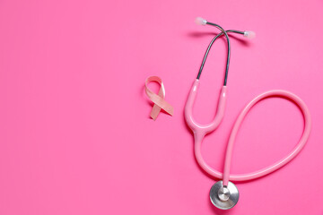 Fototapeta premium Pink awareness ribbon and stethoscope on color background, flat lay. Space for text
