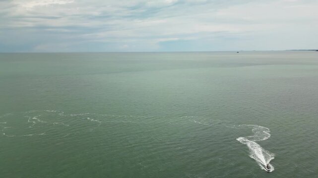 Aerial drone view over the Black Sea near Ureki Beach, Georgia, with small waves, calm water and distant coastline under a cloudy sky.