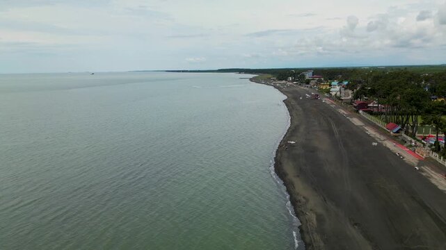 Aerial view of the curved coastline of Ureki Beach in Georgia, showing the dark sandy shore, Black Sea water and coastal settlement from above.