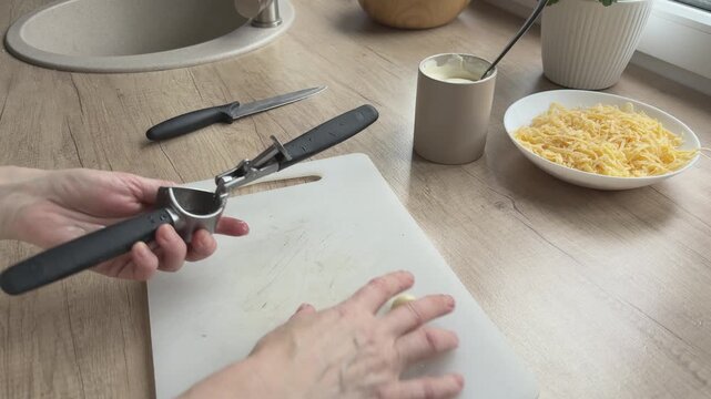 Putting garlic cloves into garlic press Preparing ingredient for sauce cooking Homemade kitchen process