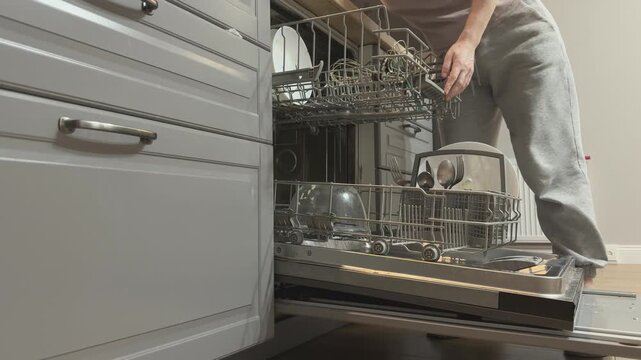 Placing dirty dishes into upper rack of dishwasher Household cleaning process organization and kitchen maintenance daily routine