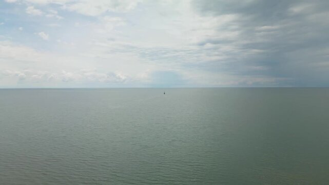 Аerial drone view over the calm sea  with soft cloudy sky and distant coastline on the horizon. Black Sea, Ureki Beach, Georgia.
