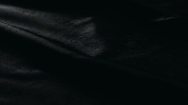 Close-up view of a dark, textured fabric with subtle folds and creases.