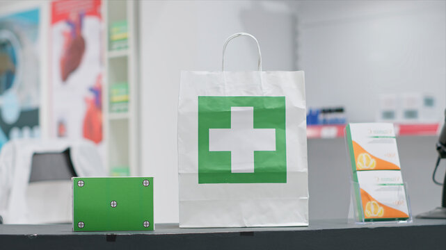 Empty pharmacy with pills and vitamins at cash register, paper bag containing pharmaceuticals alongside green screen layer on pill box at checkout area, chromakey copyspace design next to purchase.