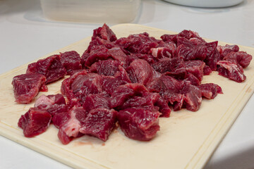 Obraz premium Fresh beef cubes rest on a wooden cutting board