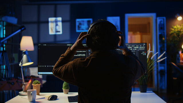 Engineer wearing headphones while using coding to fortify security, remotely working for IT company, software expert listening music and upgrading binary code scripts on computer.