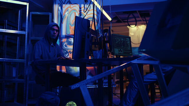 Rogue computer scientists working hard on writing lines of code on hideout PC in order to get past security systems, expert scammers building scripts that can hack devices, zoom out shot.