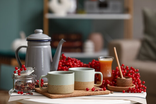 Cups of tasty viburnum tea on table in interior of living room, closeup
