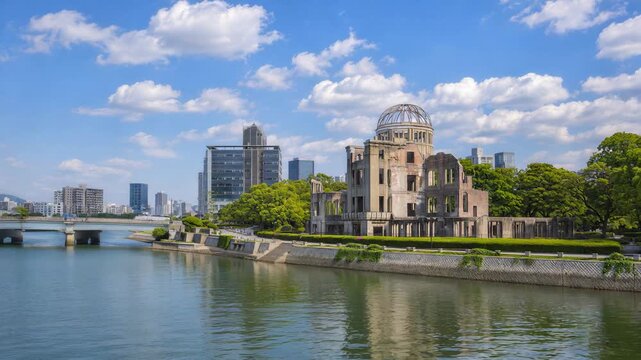Hiroshima Peace Memorial and Genbaku Dome along the river. Modern city skyline and bridge under a blue sky with white clouds