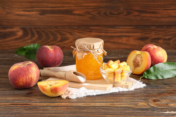 Naklejka premium Jar of jam, fresh peaches and scoop of sugar on wooden background