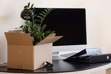 Obraz premium Workplace with computer, cardboard box and things in office on moving day