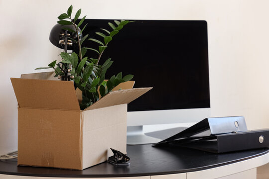 Workplace with computer, cardboard box and things in office on moving day