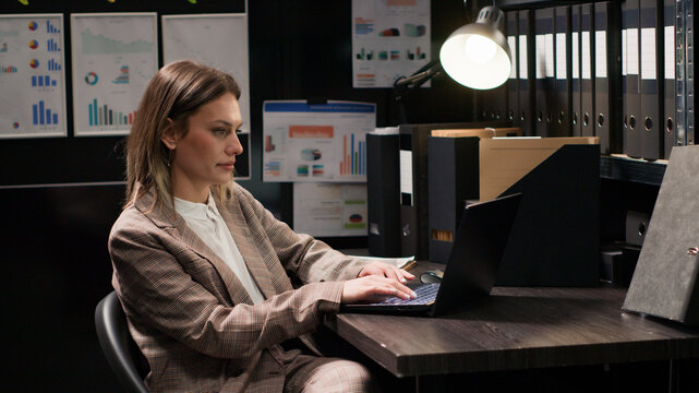 Confident female private detective investigator reviews clues in office, searching on laptop for evidence to solve crime, profile portrait of focused Caucasian policewoman using personal computer.