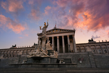 Obraz premium Austrian Parliament building at sunset. Historic famous architecture in Vienna, Austria, with magnificent glowing sky and colorful illuminated clouds