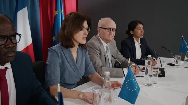 Caucasian woman speaking at international press conference with diverse diplomats listening. Clip is suitable for global news, political campaigns, and corporate communication videos