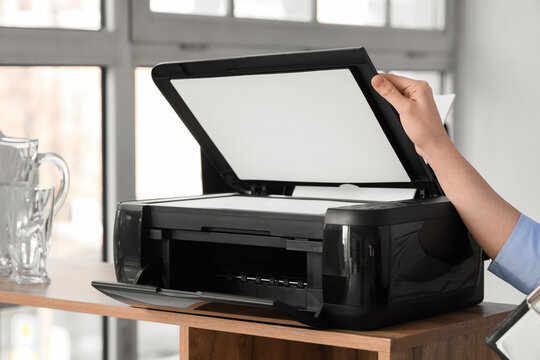 Young businesswoman using printer on shelf in office, closeup