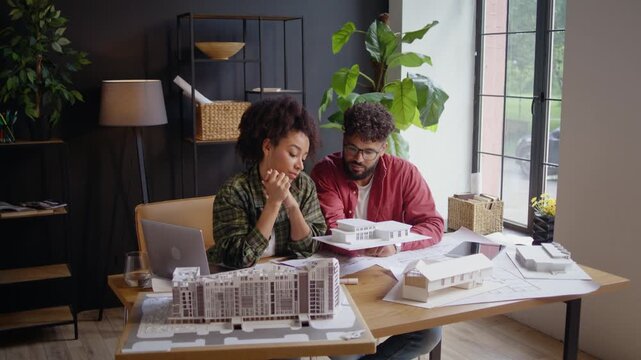 Diverse architects review mansion model and floor plans in studio