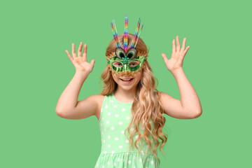 Obraz premium Adorable little girl wearing carnival mask on green background