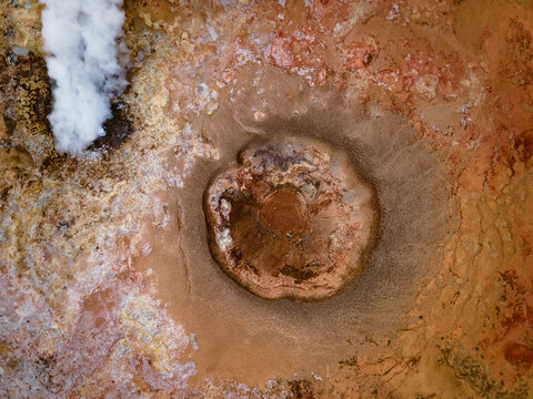 Aerial view of the Gunnuhver Hot Springs geothermal area featuring a large crater and rising steam from a vent in Grindavikurbaer, Iceland.