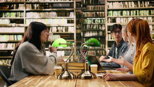 Students sharing high five in group study session at library table, celebrating academic success with collaborative learning, Diverse classmates happy with achievement, surrounded by green lamps.
