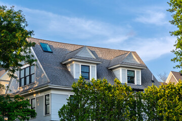 Obraz premium Traditional residential house roofline with gabled dormer windows and skylight in Brookline, Massachusetts 
