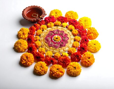 A vibrant floral arrangement in a circular pattern with a lit diya