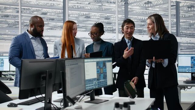 Portrait of diverse engineers reviewing microchip production operations during meeting inside factory workplace, professionals cooperating to improve semiconductor hardware performance.