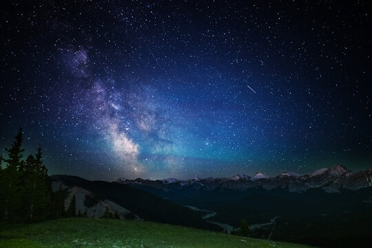 A clear, starry night with the Milky Way in the background, next to a camping tent and the rocky Canadian mountains 