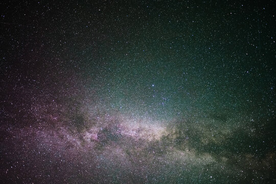 A clear, starry night with the Milky Way in the background, next to a camping tent and the rocky Canadian mountains 