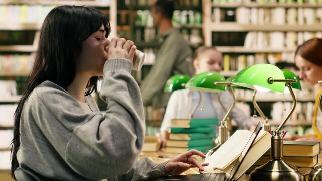 Frustrated woman student scratching head and drinking coffee, feeling exam stress and pressure while taking notes with open book and laptop.