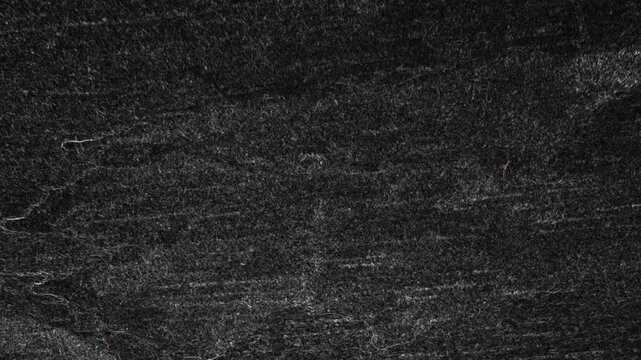Dark worn textured surface with horizontal streaks, subtle scratches, and weathered appearance throughout. Grunge texture background animation.