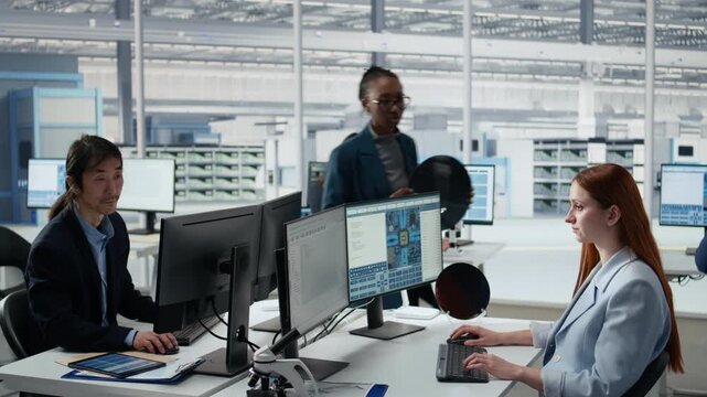 Women working together in office to examine semiconductor substrate inside microchip research facility.