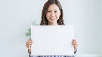 Naklejka premium 無地の白紙を両手で持つ笑顔の女性 コピースペース