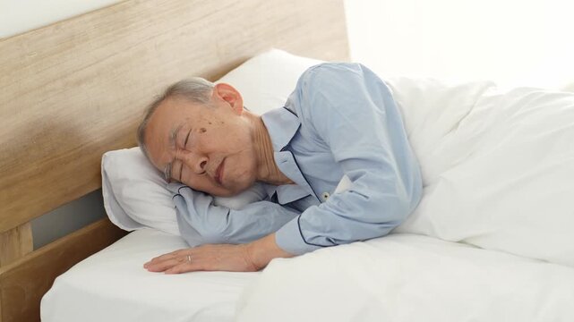 ベッドで休む体調不良の高齢者の男性